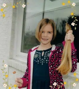 A girl holding her ponytail for donation to Wigs For Kids.