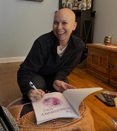 A smiling bald woman holding a copy of 