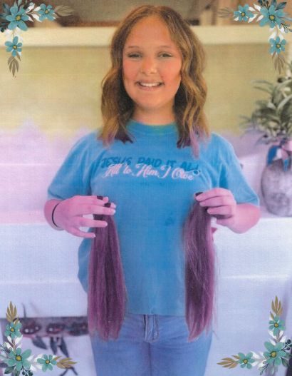 A girl holding her ponytail for donation to Wigs For Kids.